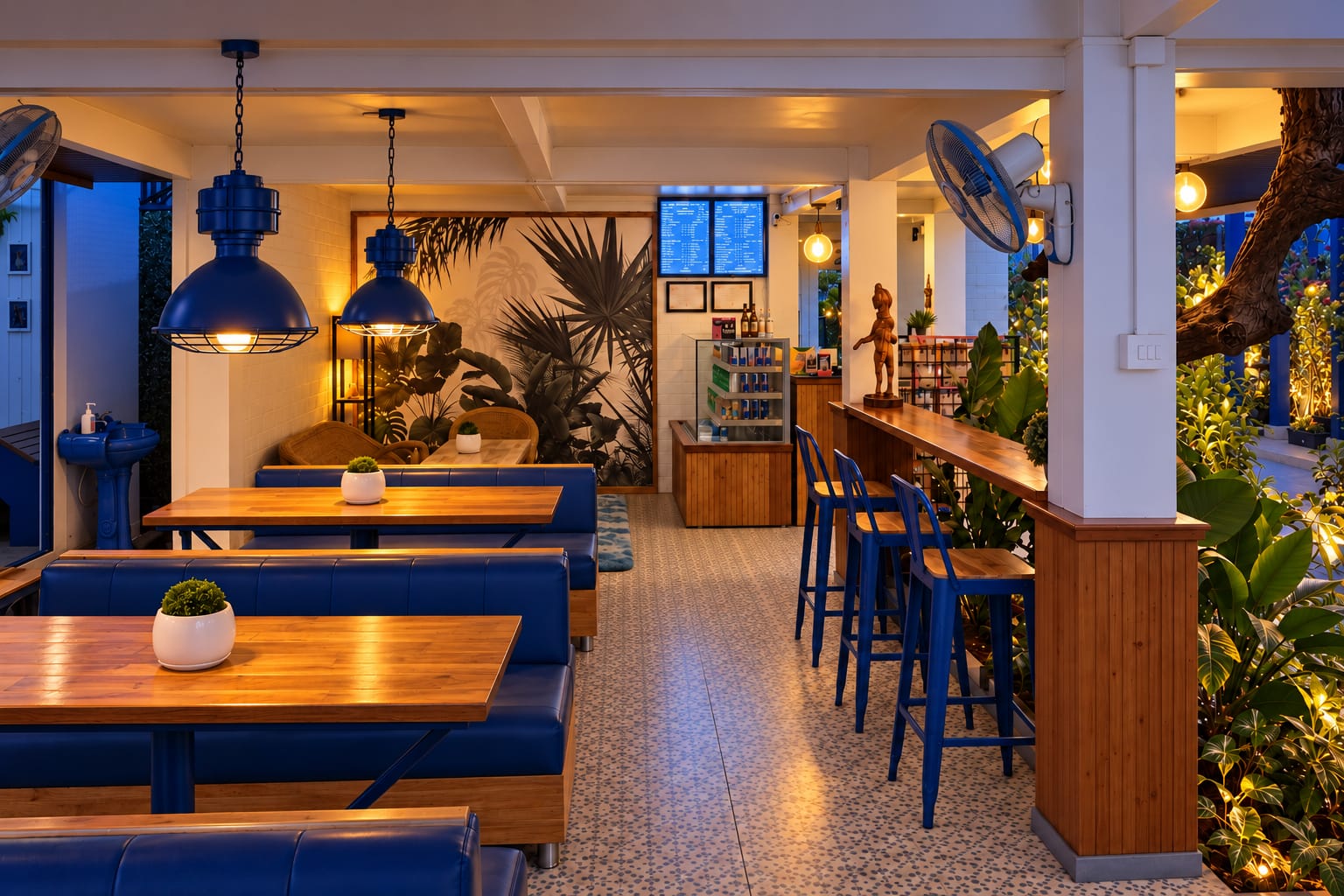 The café: wooden tables and blue benches under blue pendant lamps, a palm mural, and blue bar stools along the counter