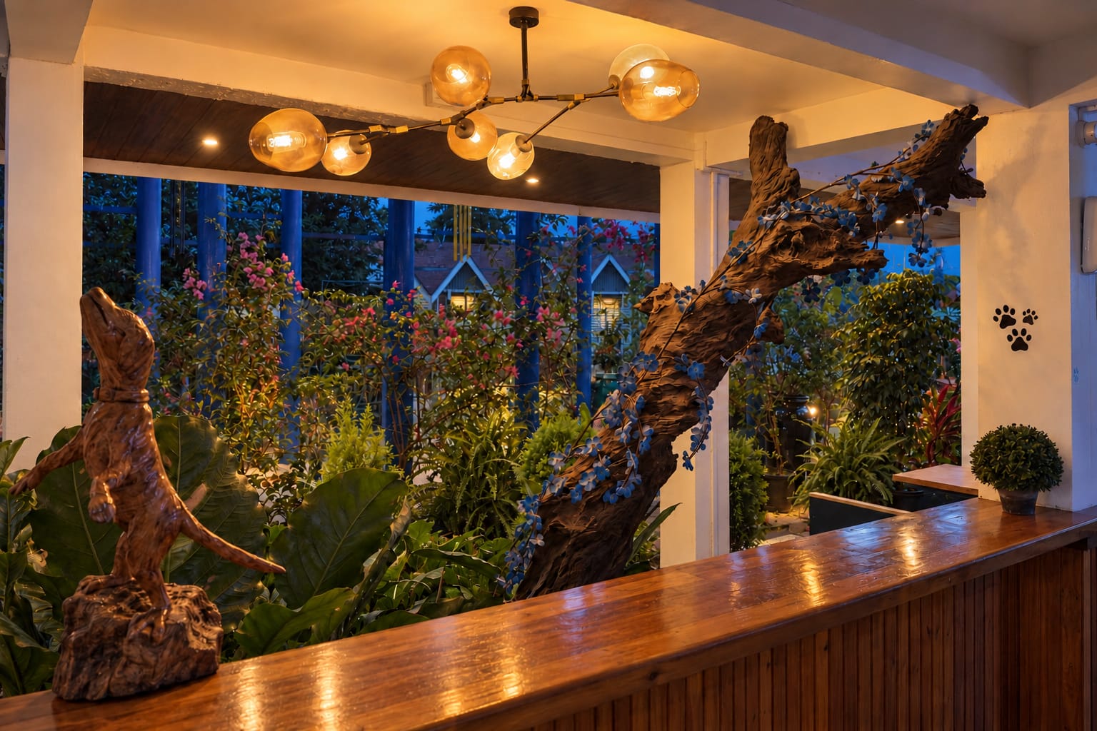 The café counter at dusk under glowing globe lamps, a carved wooden dog by the window